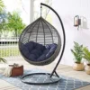 A person relaxing in a colorful swing outdoor hammock chair, surrounded by greenery.