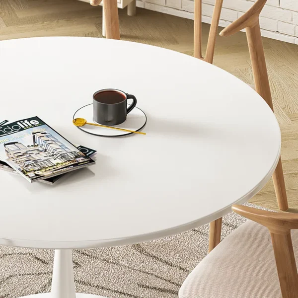 A stylish white round dining table with a smooth matte finish and tapered legs, set in a cozy dining room.