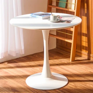 A stylish white round dining table with a smooth matte finish and tapered legs, set in a cozy dining room.